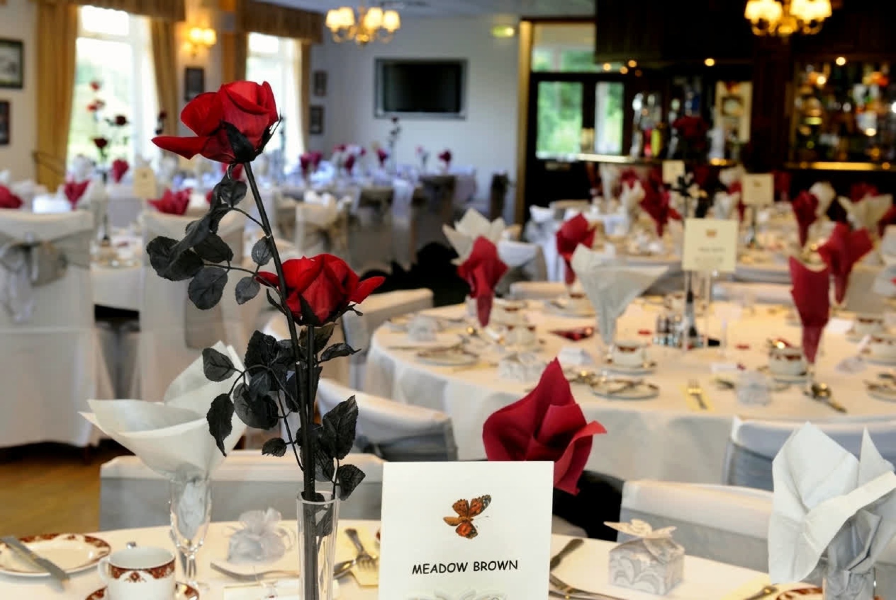 The Centenary Lounge at Dunscar dressed with white linen and red roses for a function